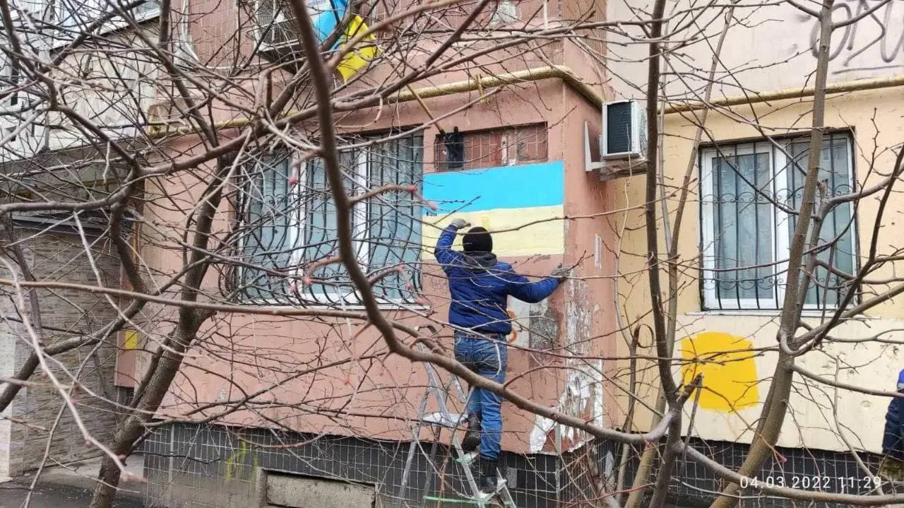 A person putting up ukraine flags on a house